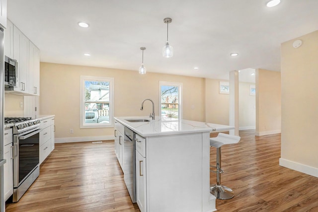 kitchen featuring stainless steel appliances, a wealth of natural light, a center island with sink, and sink