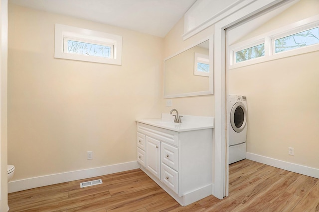 clothes washing area with washer / clothes dryer, light hardwood / wood-style flooring, and sink