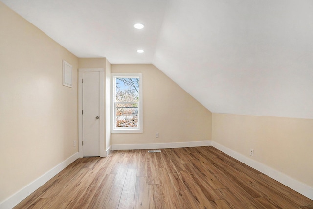 additional living space featuring light wood-type flooring and lofted ceiling