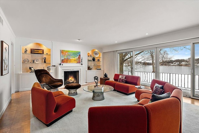 living room with crown molding, built in features, and a water view