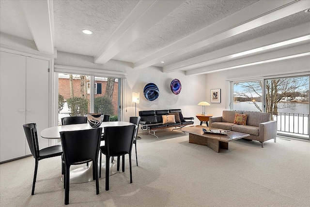 carpeted dining space with beam ceiling, a textured ceiling, and a wealth of natural light