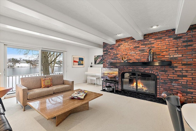 carpeted living room with beamed ceiling, a fireplace, a water view, and a textured ceiling