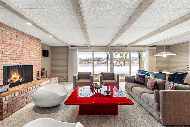 carpeted living room featuring beamed ceiling, a healthy amount of sunlight, and a fireplace