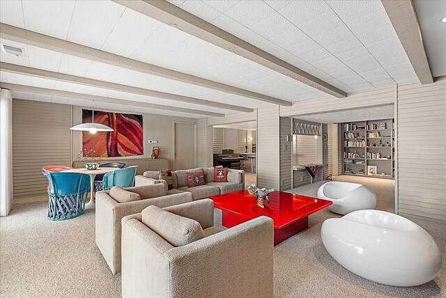 carpeted living room with built in shelves and beam ceiling