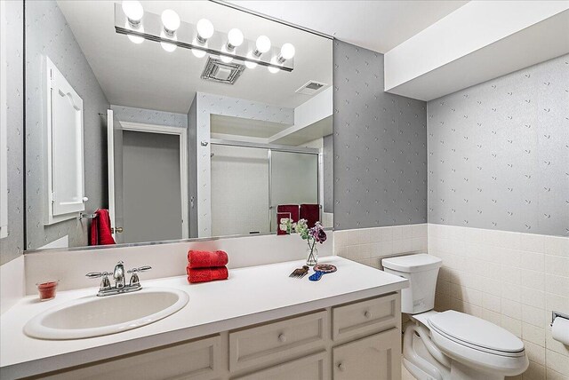 bathroom featuring toilet, vanity, tile walls, and walk in shower