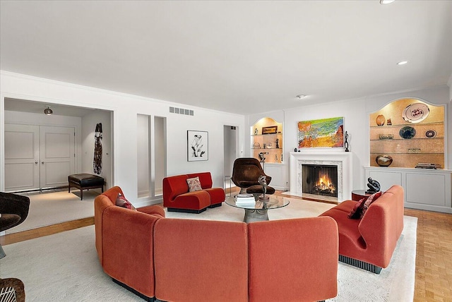 living room featuring built in shelves, a premium fireplace, and light parquet floors