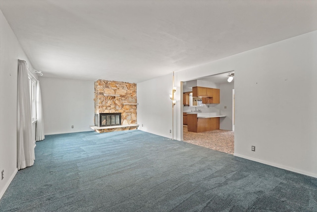 unfurnished living room with sink, a fireplace, and dark carpet