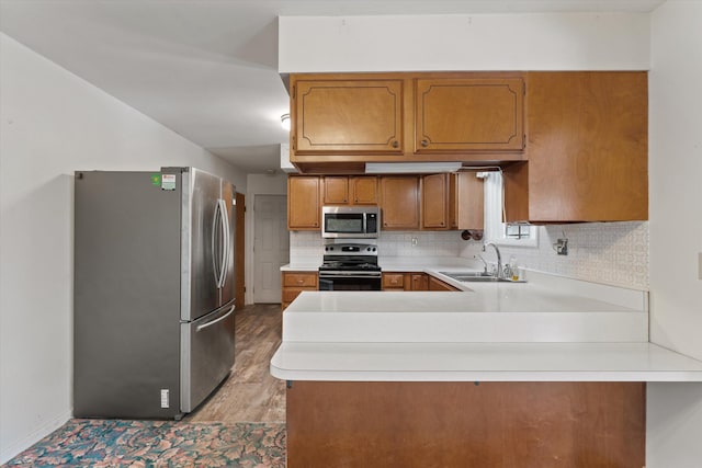 kitchen featuring kitchen peninsula, stainless steel appliances, light wood-type flooring, and sink