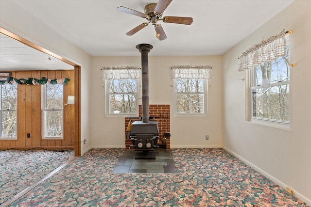 interior space with ceiling fan and a wood stove