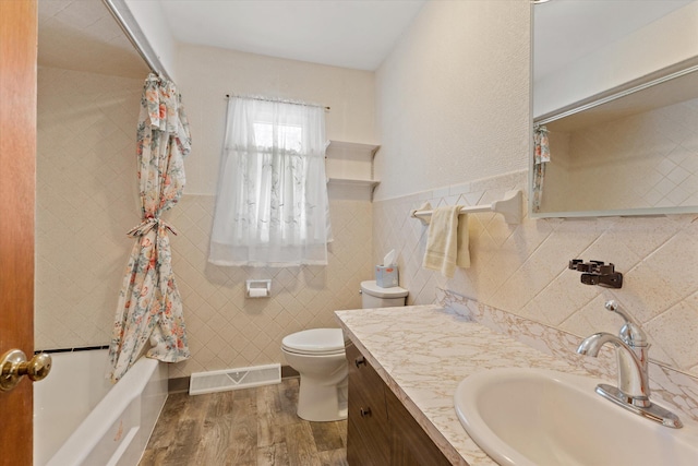 full bathroom with shower / tub combo, toilet, vanity, tile walls, and hardwood / wood-style flooring