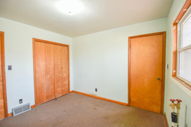 unfurnished bedroom with light colored carpet and a closet