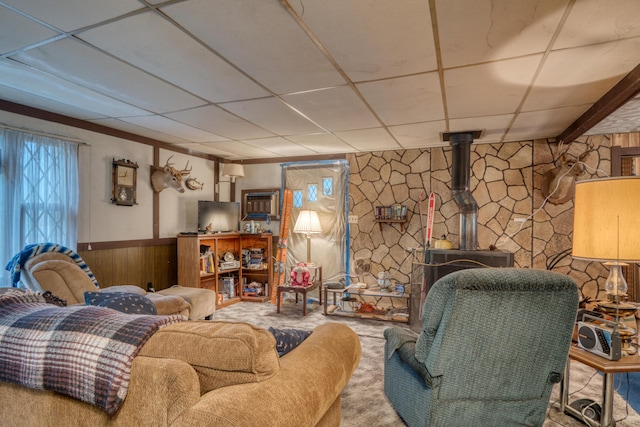 carpeted living room featuring a paneled ceiling and a wood stove