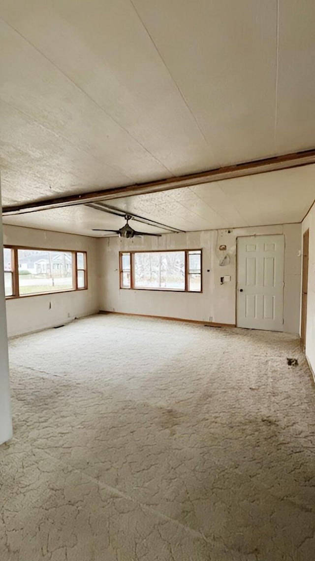 carpeted empty room with a wealth of natural light, ceiling fan, and vaulted ceiling