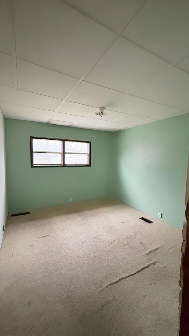 carpeted spare room with a drop ceiling