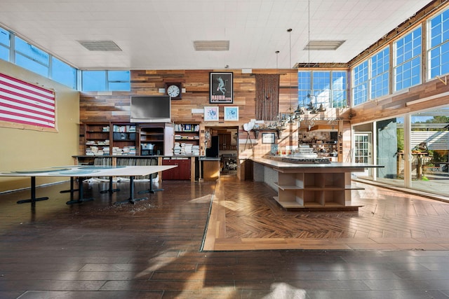 interior space featuring a towering ceiling, dark wood-type flooring, and wooden walls