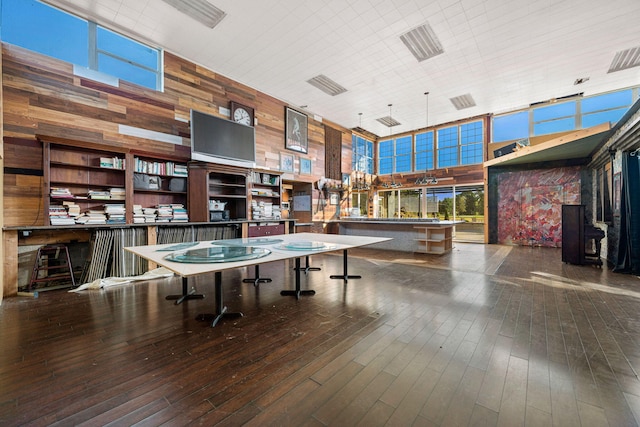 playroom featuring wood walls, wood-type flooring, and a towering ceiling