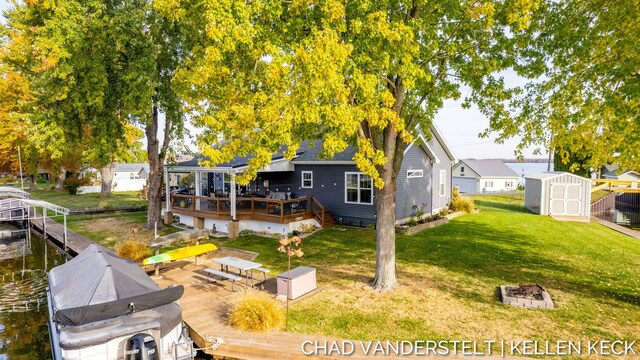 back of house featuring a lawn, a deck with water view, and a shed