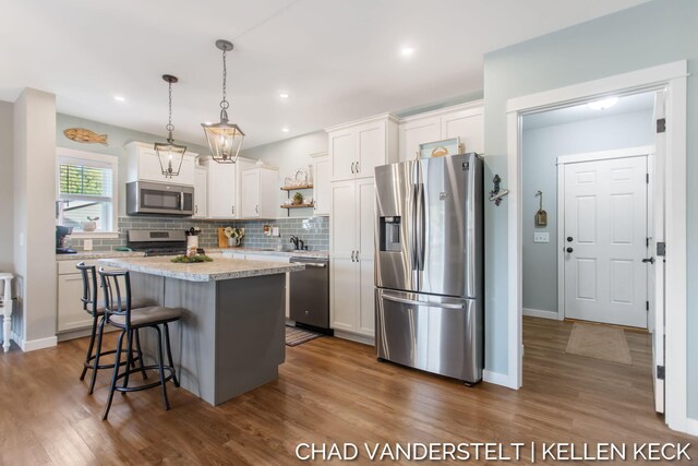 kitchen with pendant lighting, a center island, stainless steel appliances, and white cabinetry