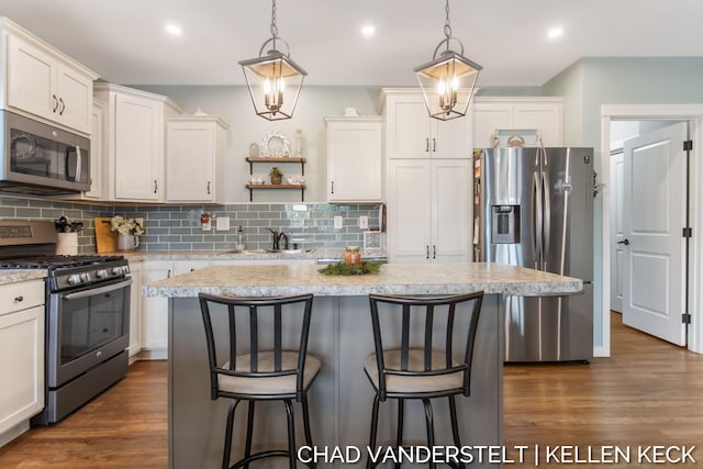 kitchen featuring appliances with stainless steel finishes, dark hardwood / wood-style flooring, decorative light fixtures, and sink