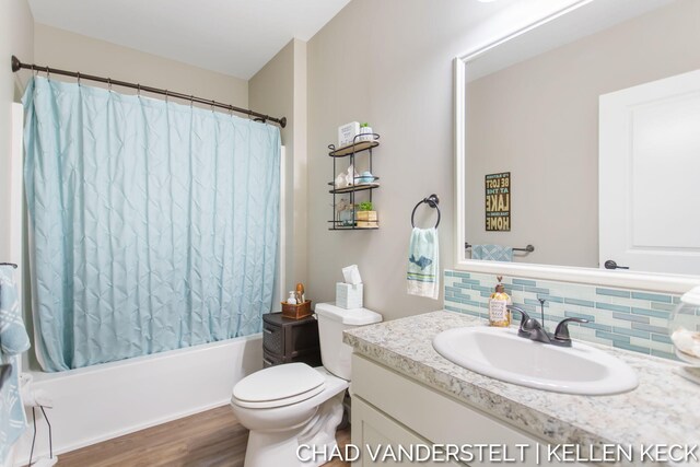 full bathroom with tasteful backsplash, vanity, shower / tub combo with curtain, hardwood / wood-style floors, and toilet