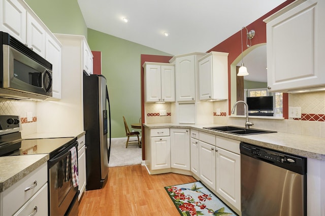 kitchen featuring sink, vaulted ceiling, appliances with stainless steel finishes, light hardwood / wood-style floors, and white cabinetry