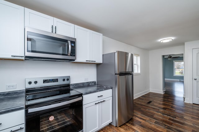 kitchen featuring appliances with stainless steel finishes, white cabinetry, ceiling fan, and dark wood-type flooring