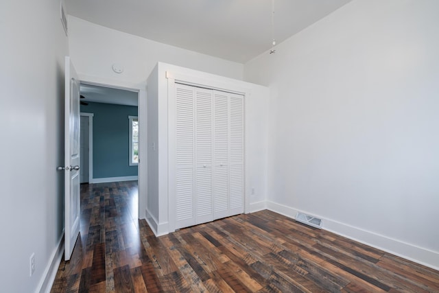 unfurnished bedroom with dark hardwood / wood-style floors and a closet