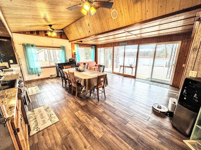 dining room with a healthy amount of sunlight, wood-type flooring, and vaulted ceiling