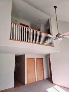 stairs with a towering ceiling, carpet floors, and ceiling fan