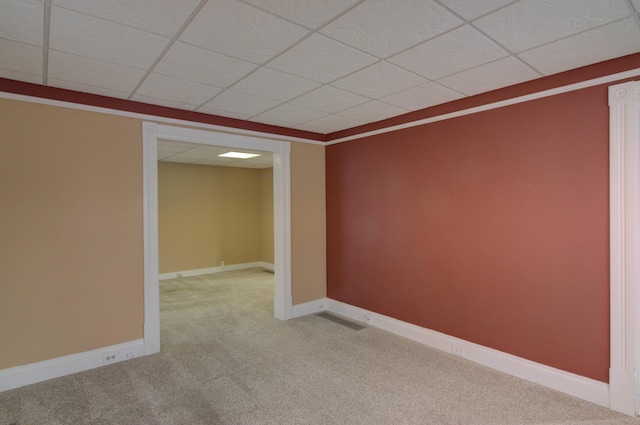 empty room featuring light colored carpet, a drop ceiling, and crown molding