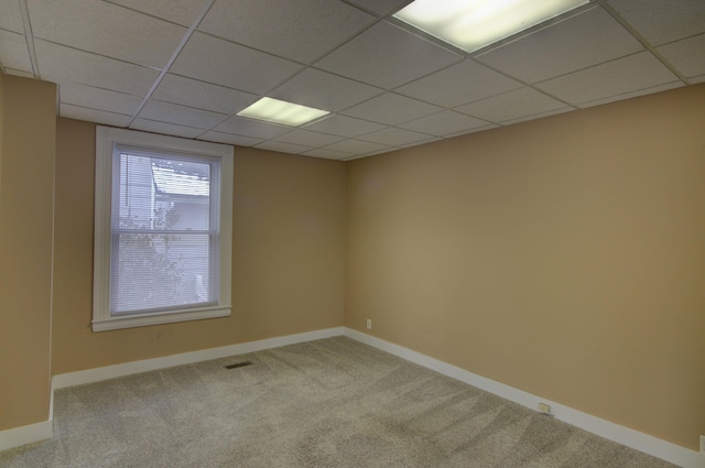 empty room with a paneled ceiling and light colored carpet