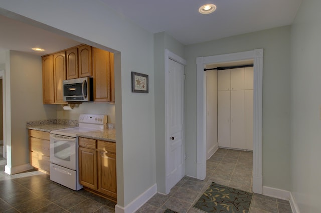 kitchen with white range with electric cooktop and dark tile patterned floors