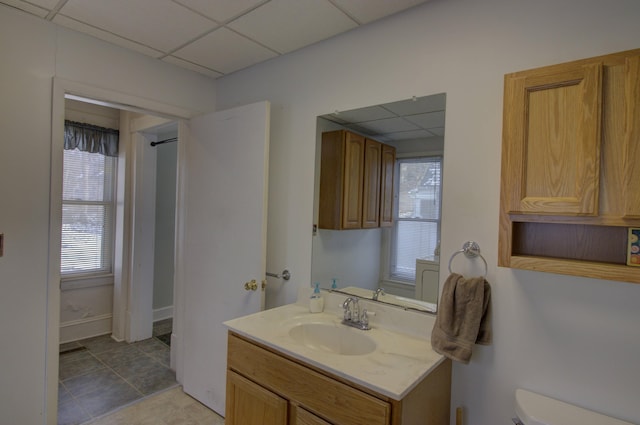 bathroom featuring tile patterned floors, a drop ceiling, and plenty of natural light