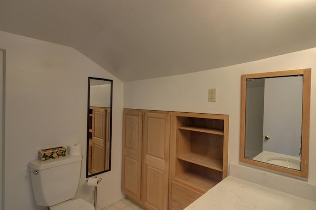 bathroom featuring tile patterned flooring, vanity, vaulted ceiling, and toilet