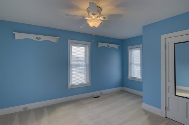 carpeted spare room featuring a wealth of natural light and ceiling fan