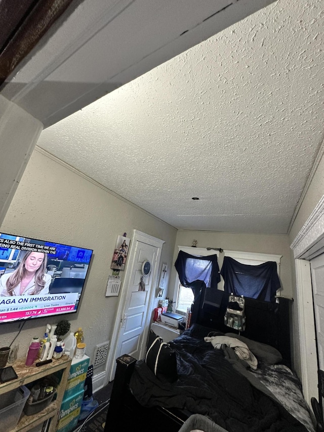 bedroom with a textured ceiling and ornamental molding