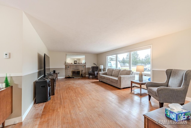 living room with light wood-type flooring and a brick fireplace