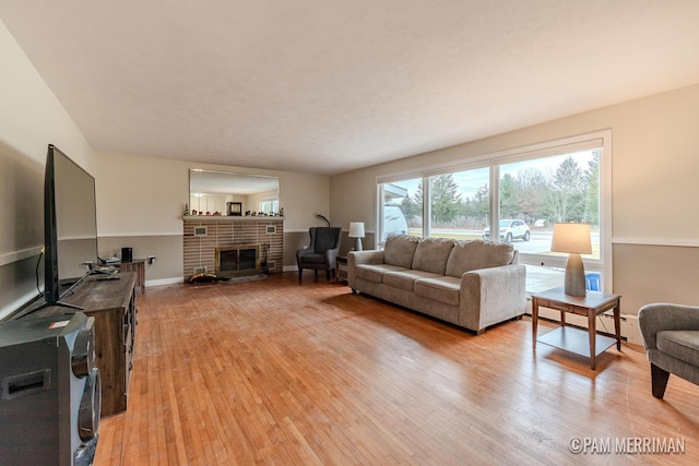 living room featuring a fireplace, light wood-type flooring, and a baseboard heating unit