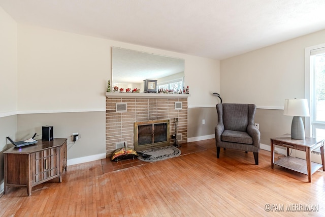 living area featuring hardwood / wood-style flooring and a brick fireplace