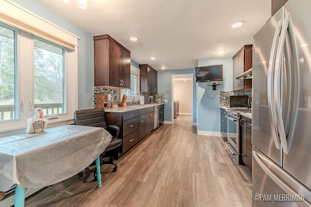 kitchen featuring light wood-type flooring, appliances with stainless steel finishes, backsplash, and exhaust hood