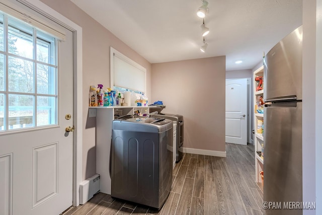 clothes washing area featuring washing machine and dryer, a baseboard radiator, and wood-type flooring