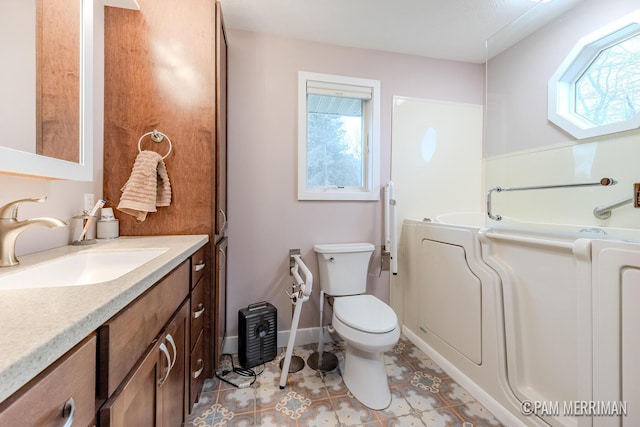 bathroom with a tub to relax in, toilet, vanity, and washer / dryer