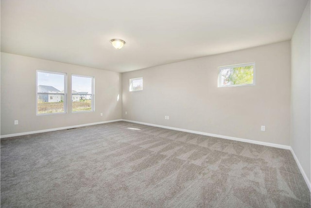 empty room featuring carpet, visible vents, and baseboards