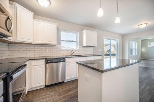 kitchen with dark wood finished floors, decorative backsplash, stainless steel appliances, and a sink