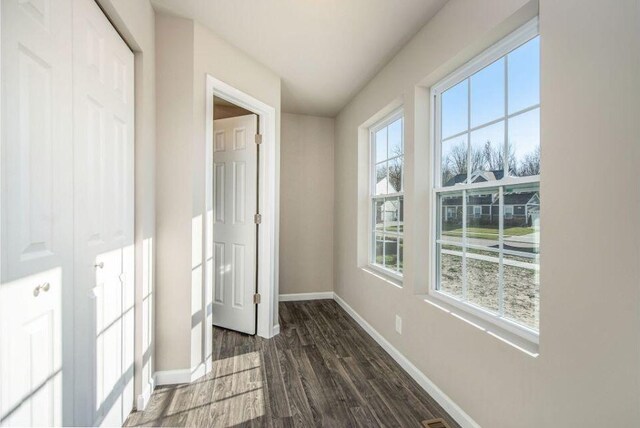 unfurnished bedroom featuring dark wood-style floors, a closet, and baseboards