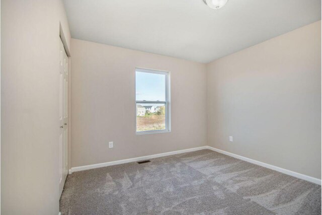 unfurnished room with carpet flooring, visible vents, and baseboards