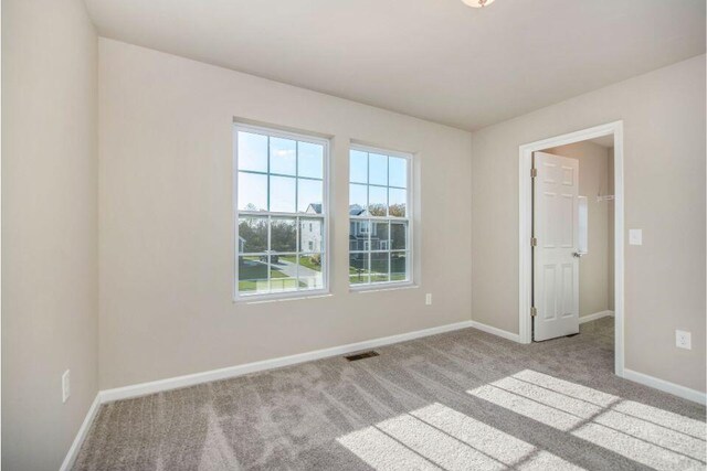 empty room with baseboards, visible vents, and carpet flooring