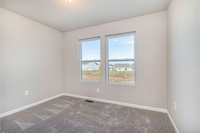 unfurnished room featuring carpet flooring, visible vents, and baseboards