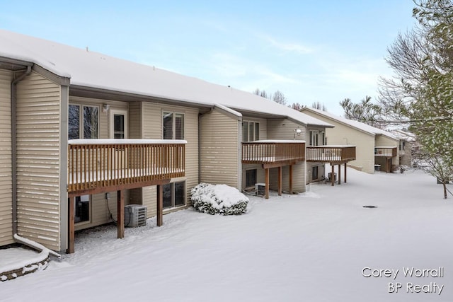 snow covered house with a deck and central AC