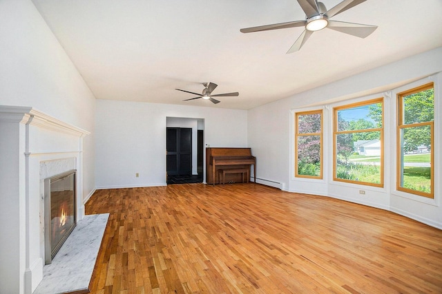 unfurnished living room featuring a fireplace, light wood-type flooring, ceiling fan, and a baseboard heating unit